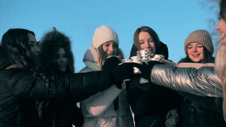 A group of girls are drinking hot tea in winter.の写真素材