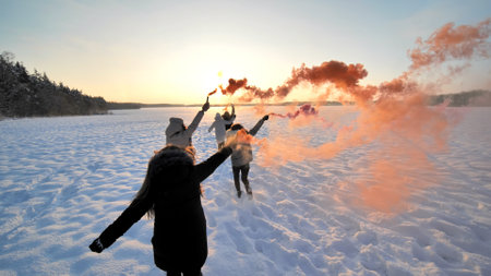Girls friends run across the winter field with colored smoke.の写真素材