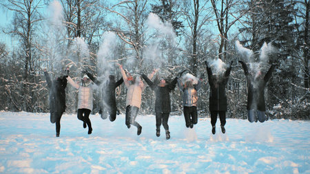 Cheerful girls throw snow on the background of a snow-covered forest.の写真素材