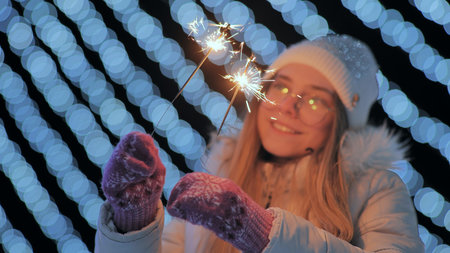 Young girl posing with sparklers against the background of New Years daisies.の写真素材
