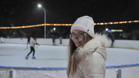 A girl watches people on a skating rink in the city.の写真素材