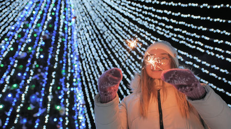 Young girl posing with sparklers against the background of New Years daisies.の写真素材