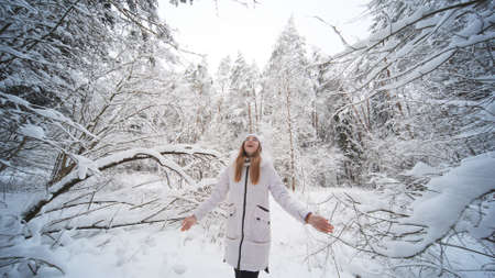 A teenage girl walks through the snowy forest.の写真素材