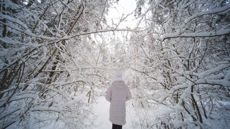 A teenage girl walks through the snowy forest.の写真素材