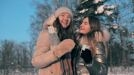 Two friends drink hot tea in winter and clink glasses.の写真素材