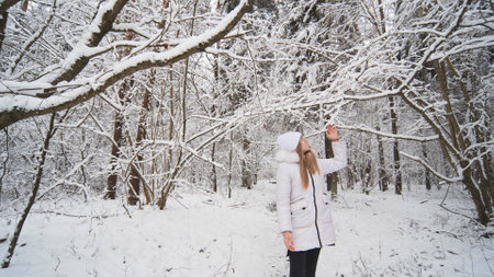 A teenage girl walks through the snowy forest.の写真素材