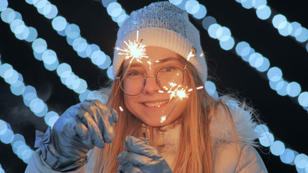 Young girl posing with sparklers against the background of New Years daisies.