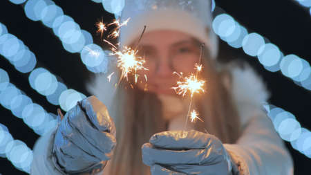 Young girl posing with sparklers against the background of New Years daisies.の写真素材