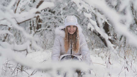 Portrait of a teenage girl sitting in a snowy fairy forest and throwing snow.の写真素材