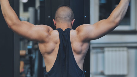 Back Workout Athlete muscular fitness male strong athletic man pumping up muscles workout...