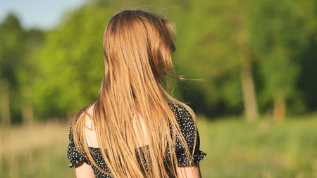 A young girl runs in a meadow on a warm summer evening.