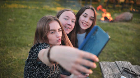 Three schoolgirls make selfies using a smartphone.の写真素材