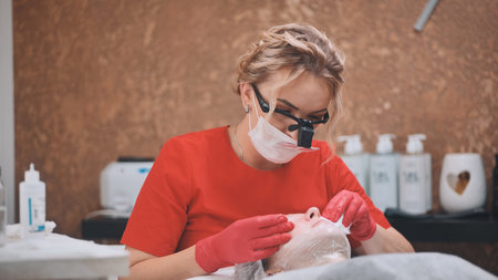 Woman beautician works with a client in a cosmetology office.の写真素材