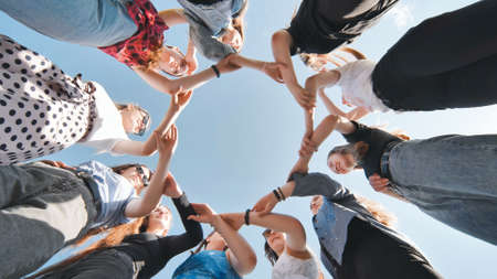 A group of girls makes a circle shape holding each others hands.の写真素材