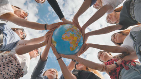Earth conservation concept. 11 girls hug the earth globe with their hands.の写真素材