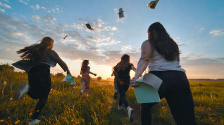 Cheerful students run throwing notebooks after school at sunset.の写真素材