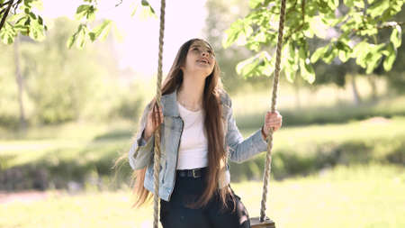 Young beautiful long-haired girl on a rope swing.の写真素材