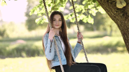 Young beautiful long-haired girl on a rope swing.の写真素材