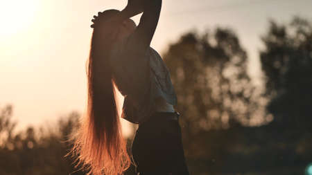Silhouette of a girl with long hair at sunset.の写真素材