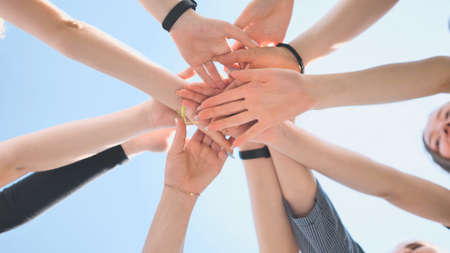 Cheerful girls join hands together as a sign of unity and joint successful work. Teamwork stacking hand concept.の写真素材