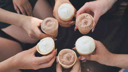 Girls friends join hands with ice cream in waffle cups in a circle.の写真素材