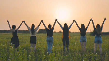 Girls friends raise their hands at sunset.の写真素材