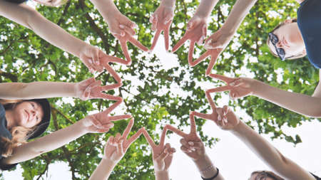 Girlfriends join fingers in a circle against the background of tree branches.の写真素材
