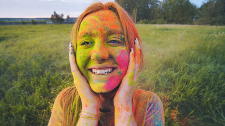 Cheerful girl posing smeared in multi-colored powder. Close-up face.