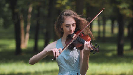 A young girl plays the violin in the city park.の写真素材