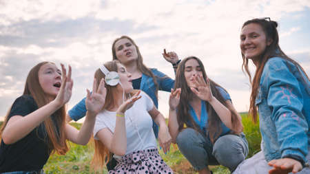 A group of girls of friends are listening to music on headphones and dancing to a friend.の写真素材