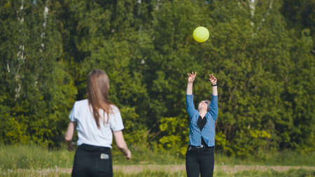 Two girlfriends play volleyball in the meadow.の写真素材