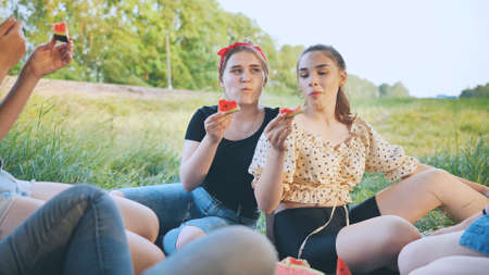 Friends have fun eating watermelon outside the city at a picnic.の写真素材