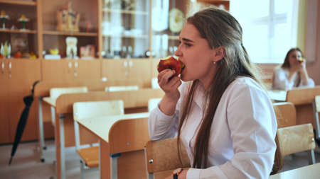 Schoolgirl eat apple in class during recess.の写真素材