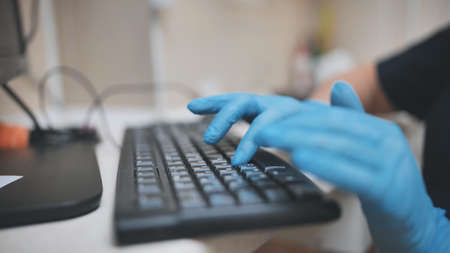 The veterinarian is typing on the keyboard in blue gloves.の写真素材