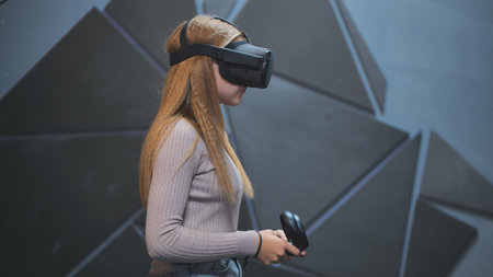 A teenage girl sits in a club with virtual glasses and plays.の写真素材