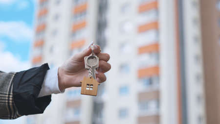 Girl holding keys to apartment against the backdrop of an apartment building.の写真素材