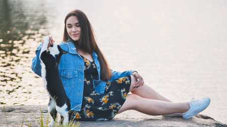 A girl plays with a cat by the lake.の写真素材