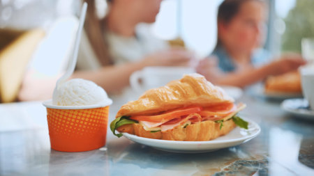 Ice cream and croissant with meat against the background of people eating in the cafe.の写真素材
