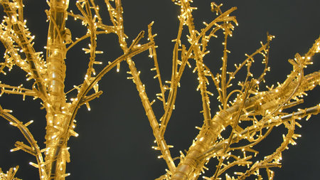 Yellow artificial Christmas tree from a garland on the streets of the city.