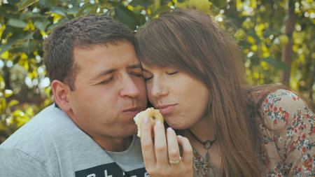 A couple in love eating apples in the orchard.の写真素材