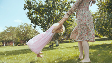 A mother circles her daughter in the garden outside the house.の写真素材