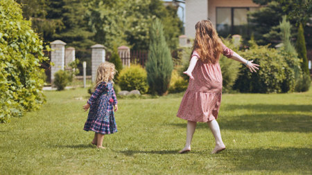 A mother and her daughter twirl in the garden outside the house.の写真素材