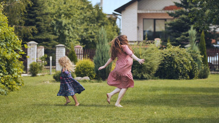 A mother and her daughter twirl in the garden outside the house.の写真素材