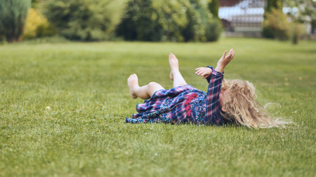 A girl is lying on the grass in the garden.の写真素材
