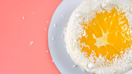 Cake with orange and coconut shavings spun on a pink background.の写真素材