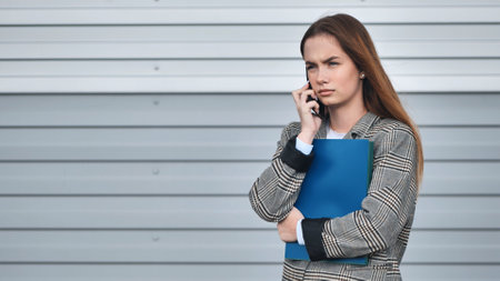 A student girl in a blazer talking on the phone.の写真素材