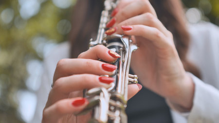 A girl plays the clarinet in the summer in the park. Close-up of her hands.の写真素材