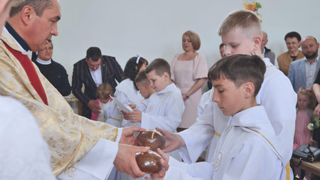 Pervomaysk, Belarus - June 17, 2022: Children take bread from the priest at their first communion...