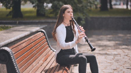 A girl plays the clarinet in the park.の写真素材