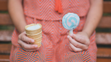 Teenage girl eating ice cream in the park on the bench. hands. Ice cream close-up.の写真素材
